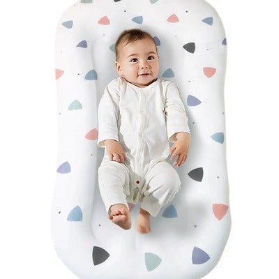 Nid d'ange portable Doux Rêves : variante à motifs géométriques colorés triangles pastel avec bébé joyeux et jouant.