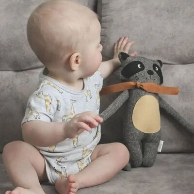 Bébé assis communiant avec Doudou Coton Bio Ultra-Doux raton laveur