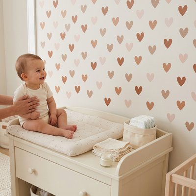 Bébé assis sur le nid d'ange posé sur commode et contemplant belle décoration stickers muraux design express