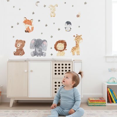 Bébé assis sur le tapis devant commode et admirant mur chambre décoré avec stickers muraux safari