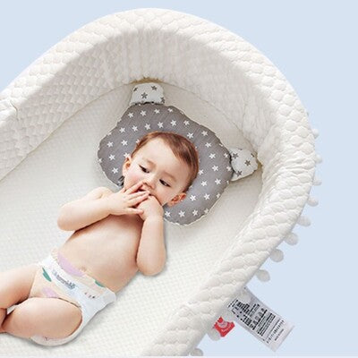 Bébé confortablement couché dans nid d ange bébé ergonomique portable profitant de oreiller inclus