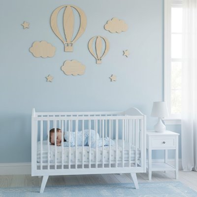 Bébé couché dans le berceau placé devant mur orné par stickers muraux design unique avec veilleuse sur commode à l'extrémité droite