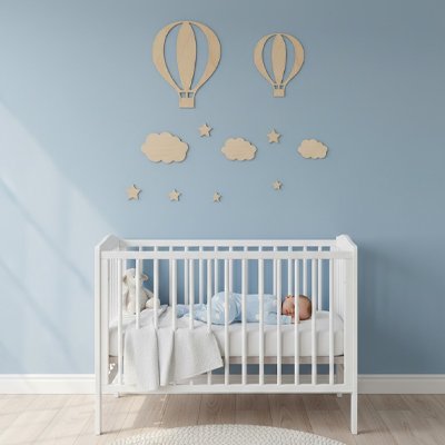 bébé couché dans le berceau placé devant mur orné par stickers muraux design unique