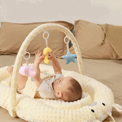 Bébé couché sur dos jouant avec jouets suspendus sur nid d'ange bébé évolutif 7 en 1