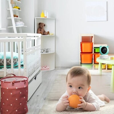 Bébé couché sur ventre et jouant avec orange dans sa chambre sous contrôle caméra bébé vision HD