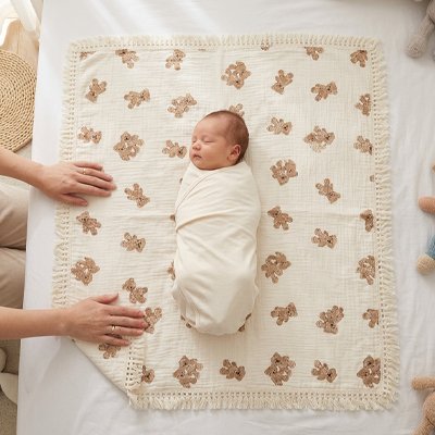 Bébé emmailloté couché sur couverture bébé douce et confortable dressée par mains adultes