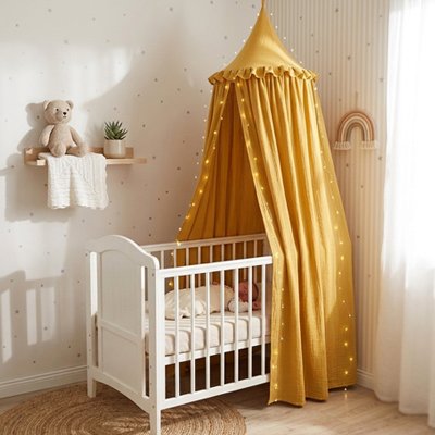 Bébé  endormi dans son berceau blanc recouvert sur largeur et décoré par ciel de lit féerique jaune 