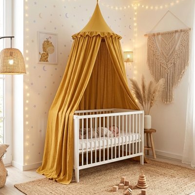 Bébé endormi dans son berceau blanc recouvert sur la longueur et décoré par ciel de lit féerique jaune 
