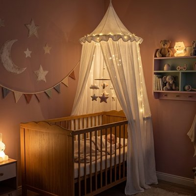 Bébé endormi dans son berceau décoré et recouvert sur la largeur par un ciel de lit atmosphère féerique beige