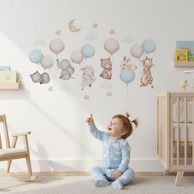 Bébé fille assise souriante et pointant du doigt mur décoré avec stickers muraux design mobile