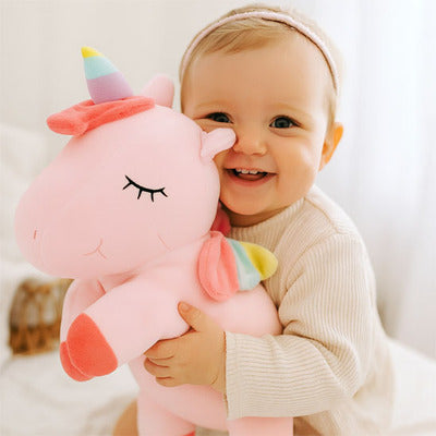Bébé heureux jouant avec peluche licorne Magique rose