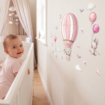 Bébé joyeux dans le berceau admirant murs chambre ornés par stickers muraux chambre décoratifs