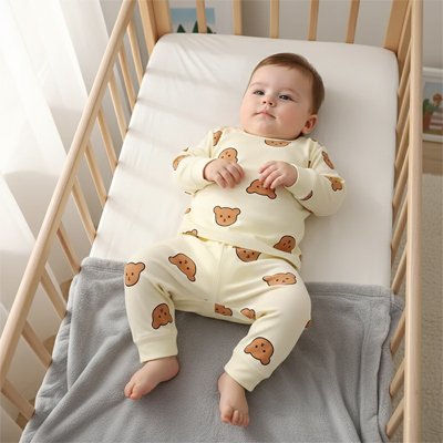 Bébé paisible allongé dans lit à barreaux portant Pyjama bébé Douceur Ultra crème motifs oursons