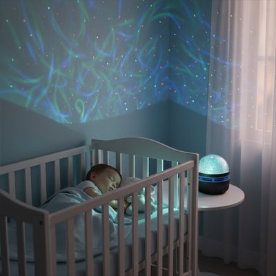 bebe profondement endormi dans chambre illuminee par veilleuse projection ciel etoile magique