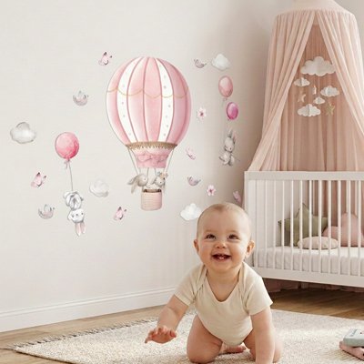 Bébé souriant à quatre pattes sur le tapis dans chambre décorée par stickers muraux chambre décoratifs