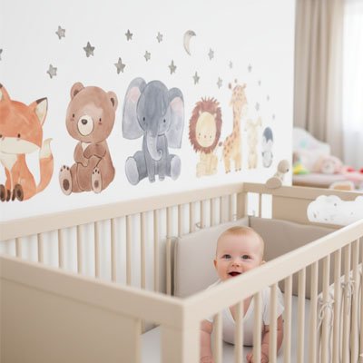 Bébé souriant à quatre pattes sur lit dans la chambre décorée avec stickers muraux safari