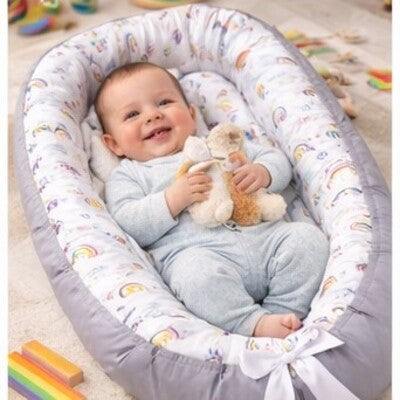 Bébé souriant dans nid d'ange bébé évolutif confort sa peluche dans ses bras