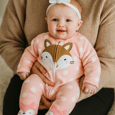 Bébé souriant porté dans bras vêtu Pyjama bébé fille Douceur Bio rose à pois avec motif renard doux et confortable pour hiver