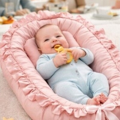 Bébé vêtu bleu tenant jouet en mains couché sur dos dans nid d'ange bébé cocon rassurant