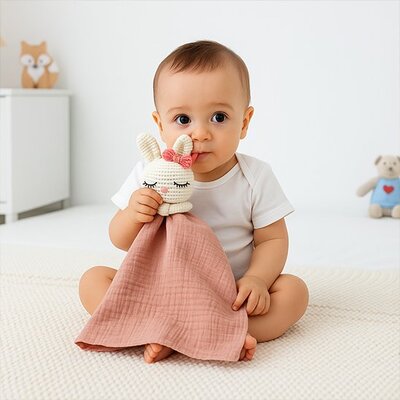 Bébé vêtu de blanc assis tenant dans bras droit Doudou bébé Doux Coton Bio