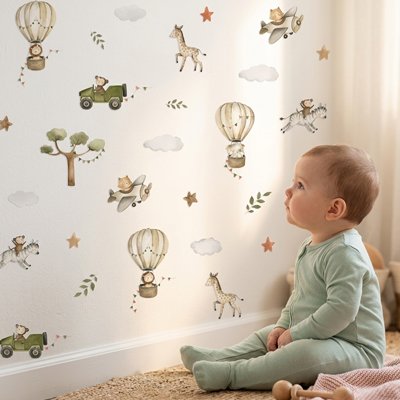 Bébé vêtu de vert assis sur tapis et admirant mur décoré par stickers muraux cocon tendance