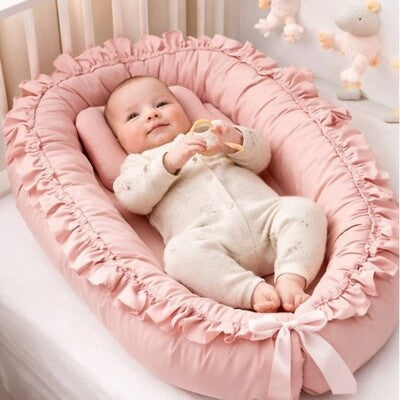 Bébé vêtu rose couché sur dos dans nid d'ange bébé cocon rassurant
