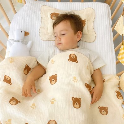 Couverture bébé Cocon Douceur en mousseline motif oursons, enfant endormi avec oreiller et canard en peluche dans le berceau