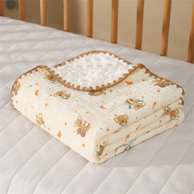 Couverture bébé Cocon Douceur large en mousseline double face, motif koalas, étoiles et lune, pliée dans le berceau