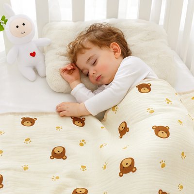 Couverture bébé Cocon Douceur à motif oursons et traces de pattes, enfant dormant avec doudou lapin sur oreiller moelleux