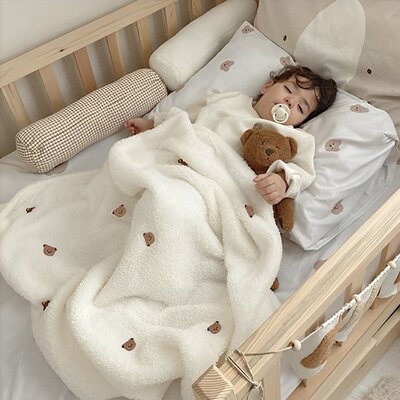 enfant endormi dans berceau couvert par couverture bebe pure douceur polaire creme brodee de tetes ours