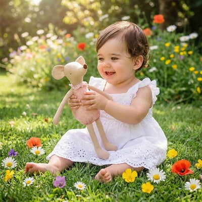 Fillette assise en pleine nature communiant avec son doudou apaisant en coton ultra-doux rose