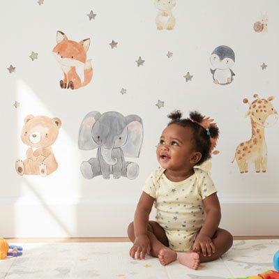 Fillette assise et heureuse admirant le mur décoré avec stickers muraux safari