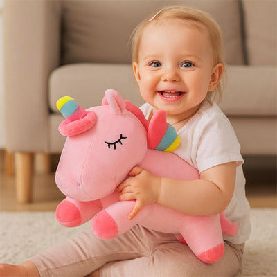 Fillette souriante réconfortée par peluche licorne Magique rose