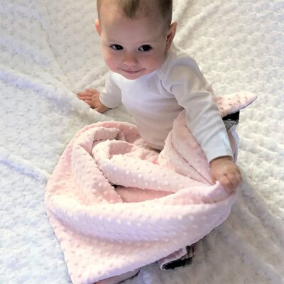 gros plan sur bebe eveille et souriant couvert par couverture bebe douceur nature minky rose