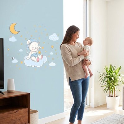 Maman communiant avec bébé dans ses bras dans la chambre décorée par stickers muraux chambre nuit magique