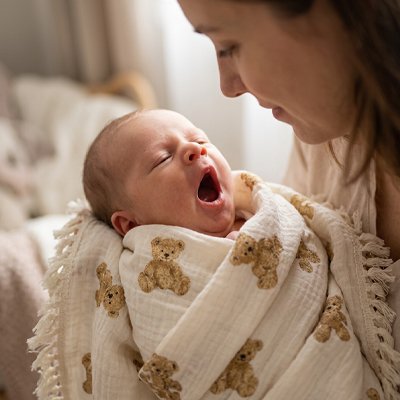 Maman debout berçant bébé baillant emmailloté dans couverture bébé douce et confortable