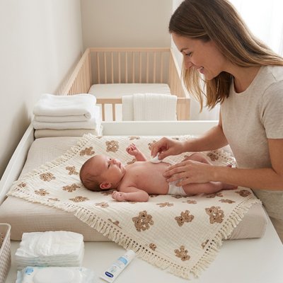 Maman debout emmaillotant bébé dans couverture bébé douce et confortable