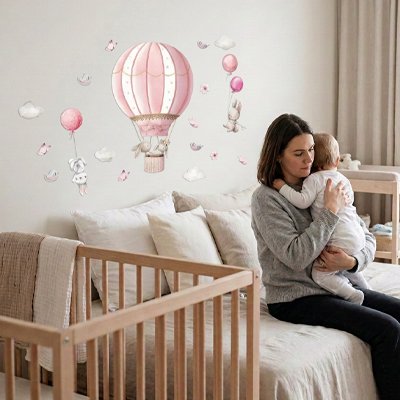 Mère assise sur le lit dans chambre décorée par stickers muraux chambre décoratifs et berçant bébé tenu contre son épaule