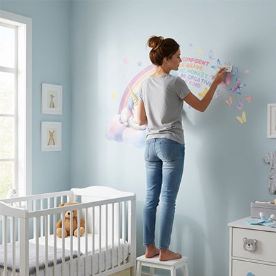 Mère décorant le mur de chambre fille avec stickers muraux enfant licorne motivante