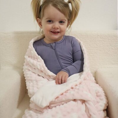 petite fillette souriante au chaud enveloppee dans couverture bebe douceur nature minky rose a  bulles