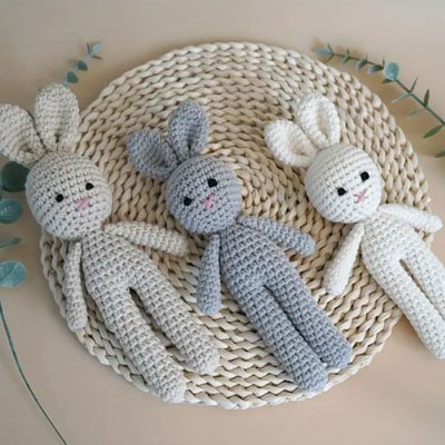 Trois variantes beige, blanche et gris-bleu du Doudou lapin câlin apaisant étalées