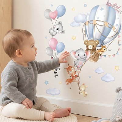 Vue de profil bébé assis touchant mur décoré par stickers muraux chambre pose facile