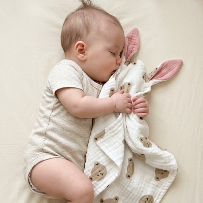 Vue face de bébé endormi avec doudou confident rassurant tête ourson dans les bras