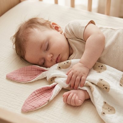 Vue profil droit de bébé endormi avec doudou confident rassurant tête ourson dans les bras