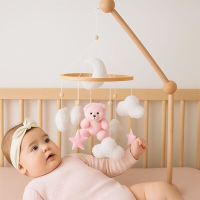 Vue profil droit de bébé vêtu de rose clair couché dans son lit et fasciné par mobile bébé musical relaxant