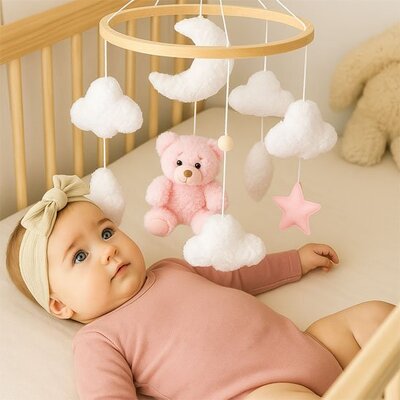 Vue profil droit de bébé vêtu de rose foncé couché dans son lit et attiré par mobile bébé musical relaxant