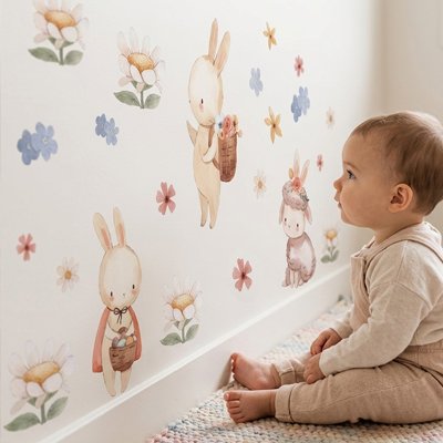 Vue profil gauche bébé assis regardant avec admiration mur orné par stickers muraux chambre déco raffinée