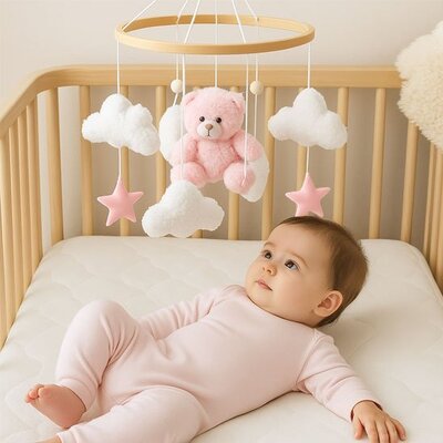 Vue profil gauche de bébé vêtu de rose clair couché dans son lit et séduit par mobile bébé musical relaxant
